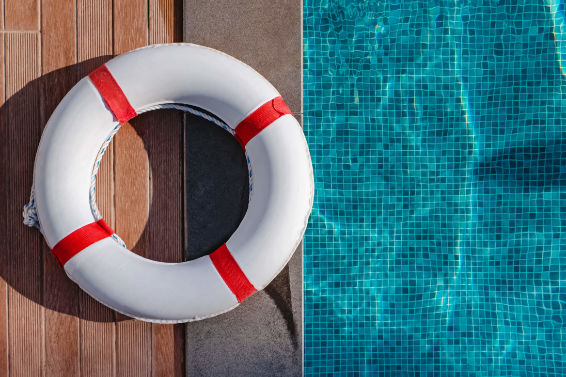 Red and white lifesaver ring next to pool